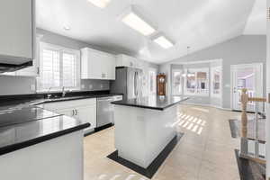 Kitchen with light tile patterned floors, stainless steel appliances, white cabinetry, and dark granite countertops