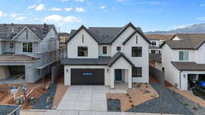 View of front of home featuring an attached garage, a tiled roof, stucco siding, driveway, and a mountain view