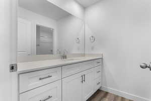 Bathroom featuring vanity, wood finished floors, and baseboards