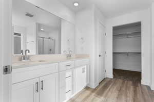 Bathroom featuring double vanity, visible vents, a shower stall, and a sink