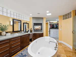 Primary bathroom with double sided fireplace and adjacent walk-in closet