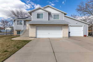 Tri-level home featuring roof mounted solar panels, fence, concrete driveway, a shingled roof, and brick siding