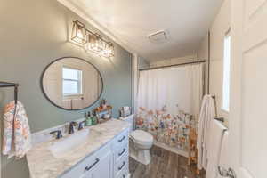 Bathroom featuring toilet, vanity, a shower with curtain, wood finished floors, and a textured ceiling