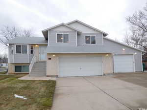 Split level home featuring brick siding, driveway, and a shingled roof