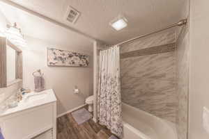 Bathroom featuring visible vents, toilet, a textured ceiling, wood finished floors, and vanity