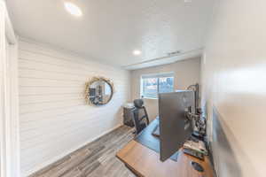 Home office with visible vents, a textured ceiling, wood finished floors, and wooden walls