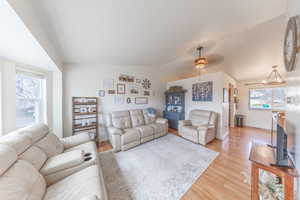 Living area with a healthy amount of sunlight, baseboards, light wood-style floors, and vaulted ceiling