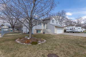 View of home's exterior featuring fence, driveway, a garage, a lawn, and brick siding