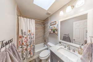 Bathroom featuring vanity, visible vents, a skylight, shower / tub combo, and toilet