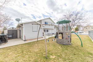 Back of property with a lawn, a playground, fence, a shed, and an outdoor structure