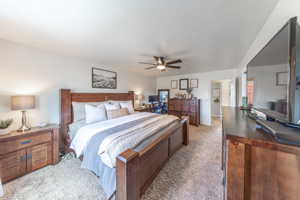 Bedroom with light carpet, a textured ceiling, and ceiling fan