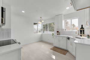 Kitchen featuring tasteful backsplash, baseboards, recessed lighting, white cabinetry, and a sink