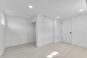 Basement featuring recessed lighting, visible vents, light wood-style flooring, and baseboards