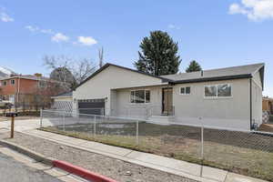 Ranch-style house featuring driveway, a garage, brick siding, and a fenced front yard