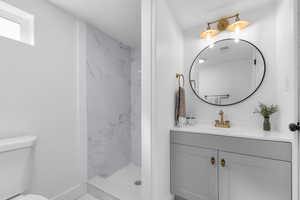 Full bathroom featuring visible vents, toilet, a shower stall, baseboards, and vanity