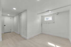 Below grade area with light wood-style flooring, recessed lighting, baseboards, and visible vents