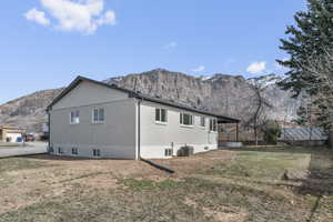 Rear view of house featuring a mountain view, a yard, brick siding, and central AC