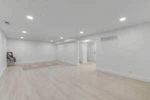 Finished below grade area with recessed lighting, visible vents, and light wood-style floors