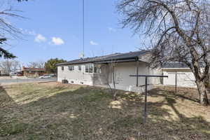 Back of property featuring a yard, brick siding, cooling unit, and fence