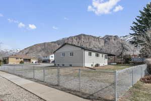 View of side of home with fence private yard, a mountain view, and central AC