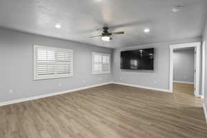 Unfurnished room featuring a ceiling fan, wood finished floors, baseboards, and a textured ceiling