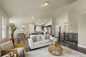 Living room with dark wood-style floors, a notable chandelier, recessed lighting, and lofted ceiling