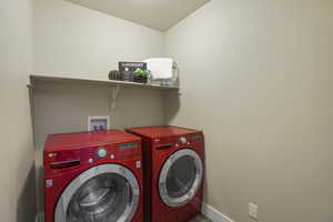 Laundry room with laundry area, washing machine and dryer, a textured ceiling, and baseboards