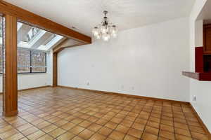 Unfurnished room with a skylight, baseboards, visible vents, and a chandelier