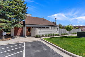 View of front facade featuring roof with shingles, uncovered parking, a front yard, and fence