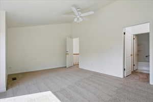 Unfurnished bedroom with baseboards, visible vents, high vaulted ceiling, ensuite bath, and carpet flooring