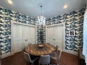 Dining area featuring a notable chandelier, wallpapered walls, and baseboards