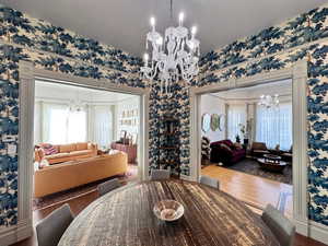 Dining area featuring a chandelier, wallpapered walls, and wood finished floors