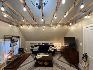 Living area featuring lofted ceiling with beams, baseboards, and track lighting