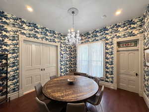 Dining room with wallpapered walls, baseboards, and a chandelier