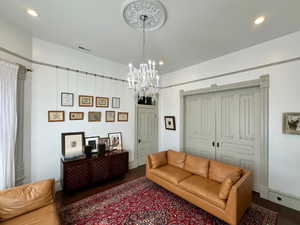 Living room with recessed lighting, visible vents, dark wood-style floors, and a chandelier
