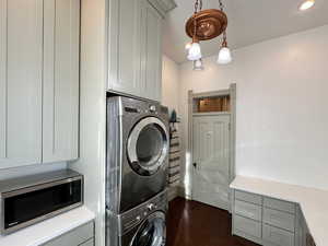 Clothes washing area featuring recessed lighting, dark wood-type flooring, stacked washer and dryer, and laundry area
