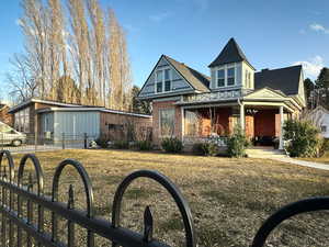 View of front of home with a sink, brick siding, a porch, and fence