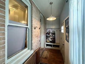 Corridor with dark wood-type flooring and brick wall