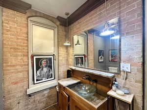 Bathroom featuring brick wall and crown molding