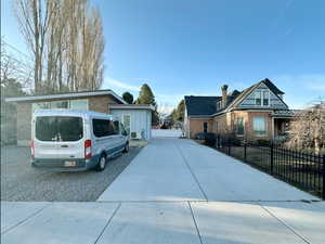 View of front facade with brick siding, concrete driveway, and fence