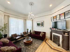 Living room with a tiled fireplace, an inviting chandelier, and wood finished floors
