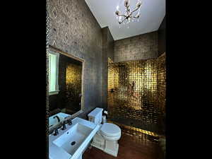 Bathroom with a chandelier, wood finished floors, toilet, and a sink