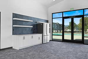 Kitchen featuring freestanding refrigerator, a sink, light countertops, white cabinets, and dark carpet