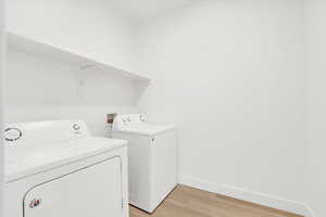 Clothes washing area featuring laundry area, independent washer and dryer, baseboards, and light wood-style floors