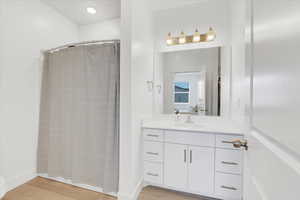 Bathroom featuring baseboards, vanity, a shower with curtain, and wood finished floors