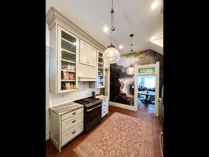 Kitchen featuring glass insert cabinets, pendant lighting, stainless steel range with gas cooktop, and light stone counters