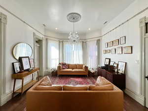 Living area with visible vents, baseboards, a notable chandelier, and dark wood finished floors