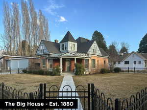 Victorian home featuring a front lawn, a gate, brick siding, and a fenced front yard