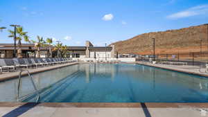 Community pool with a patio area, a mountain view, and fence