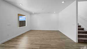 Empty room featuring stairs, recessed lighting, wood finished floors, and baseboards